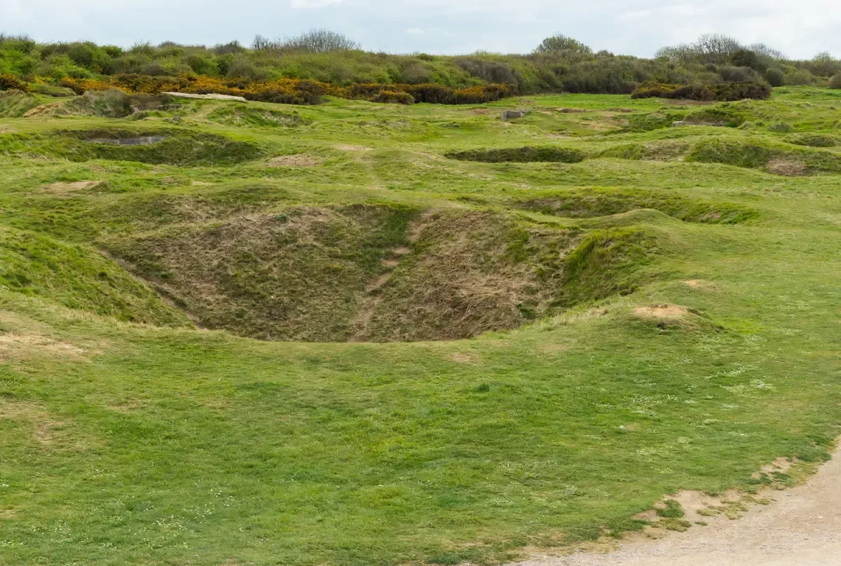 Grass-covered bomb craters at Pointe du Hoc in Normandy, a stop on a D-Day day tour from Paris